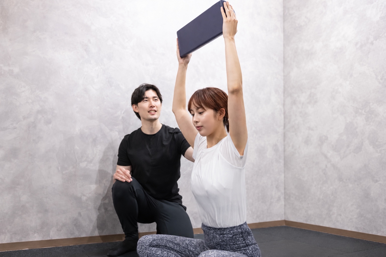 トレーナーと一緒に、腕を上げる動きを確認しながらエクササイズする様子